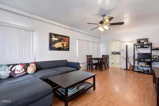 a living room with furniture and a flat screen tv with kitchen view