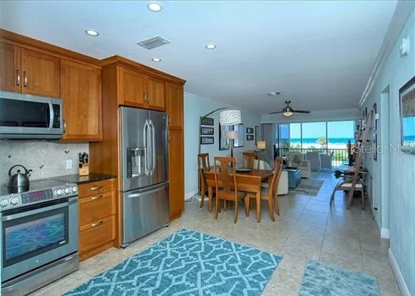 a kitchen with stainless steel appliances granite countertop a refrigerator dining table and chairs