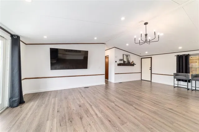 a view of a dining room and livingroom with furniture wooden floor a chandelier