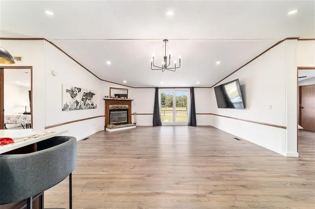 a kitchen with stainless steel appliances granite countertop a refrigerator a sink a stove and white cabinets with wooden floor