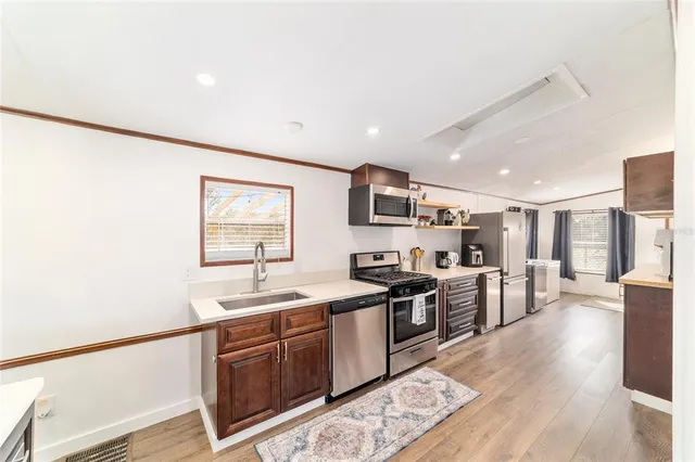 a kitchen with stainless steel appliances granite countertop a refrigerator a stove and a sink with wooden floor