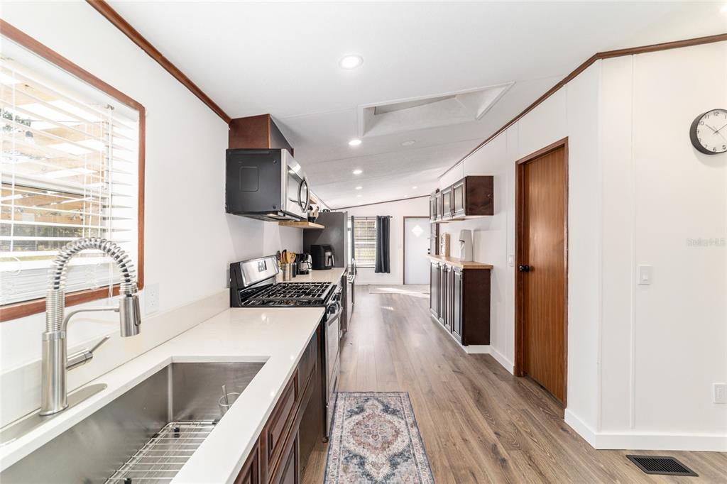 5150 Southeast 117th Avenue Morriston, FL 32668 - Photo 22 of 63 a kitchen with stainless steel appliances granite countertop a refrigerator a sink a stove and white cabinets with wooden floor