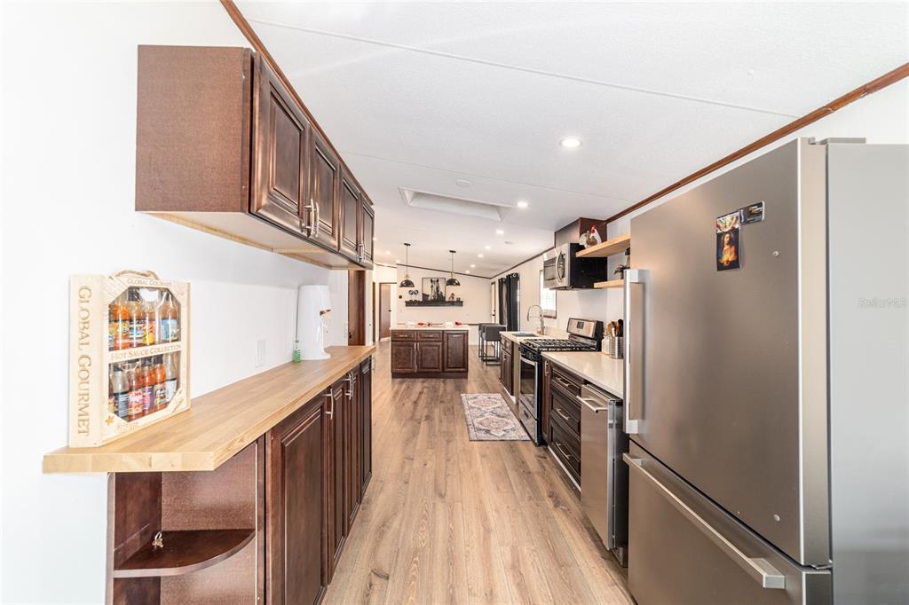 5150 Southeast 117th Avenue Morriston, FL 32668 - Photo 24 of 63 a kitchen with stainless steel appliances granite countertop a refrigerator a stove and a sink with wooden floor