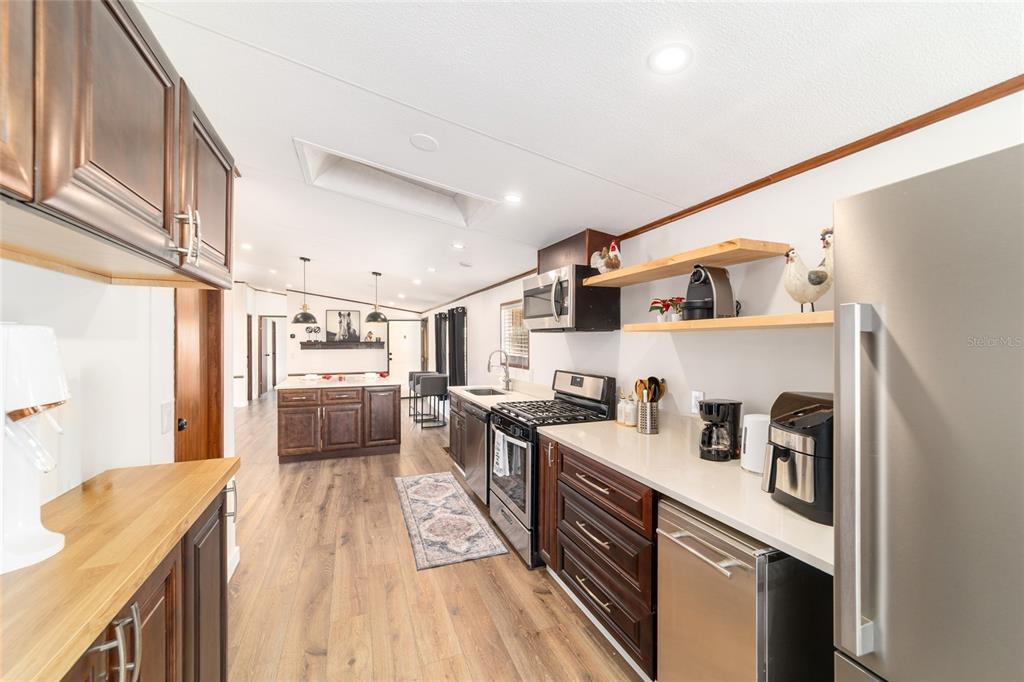 5150 Southeast 117th Avenue Morriston, FL 32668 - Photo 27 of 63 a kitchen with stainless steel appliances a sink a stove a refrigerator cabinets and a counter top space
