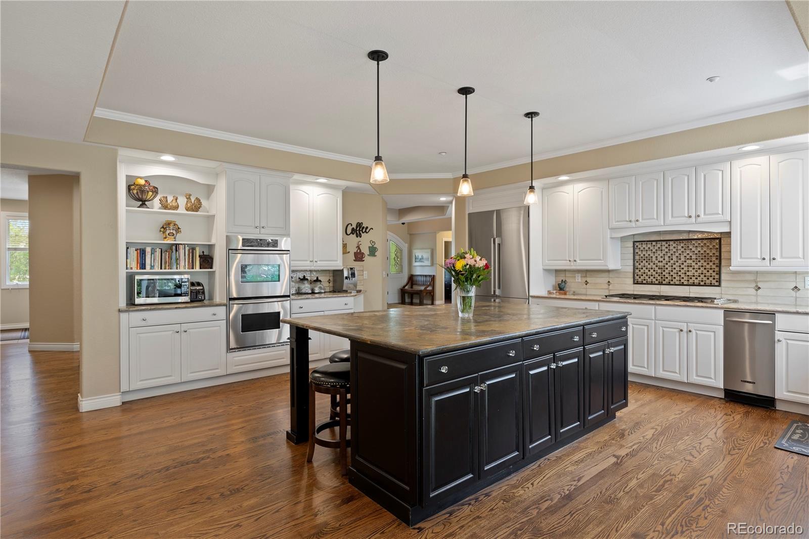 315 Prospect Drive Castle Rock, CO 80108 - Photo 11 of 45 a kitchen with stainless steel appliances granite countertop wooden floors and white cabinets