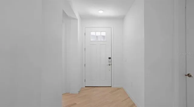 a view of an empty room with wooden floor and a window