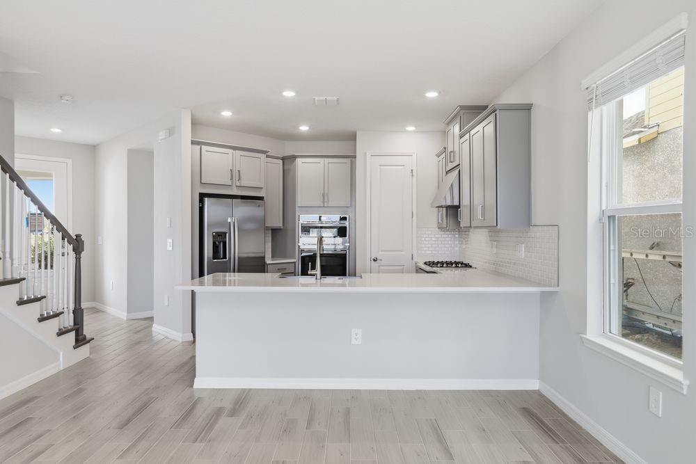 1014 Top Minnow Road St. Cloud, FL 34771 - Photo 3 of 39 a large kitchen with stainless steel appliances a large counter top and a wooden floors