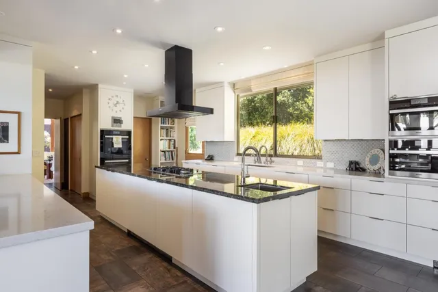 a large kitchen with kitchen island granite countertop a large window and a counter space