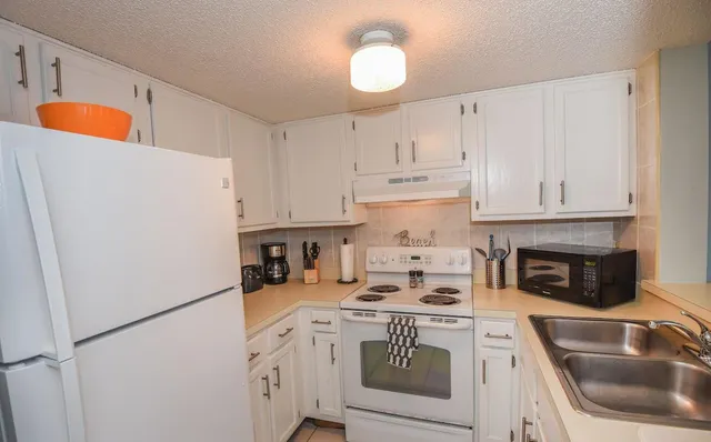 a kitchen with a refrigerator a stove a sink and cabinets