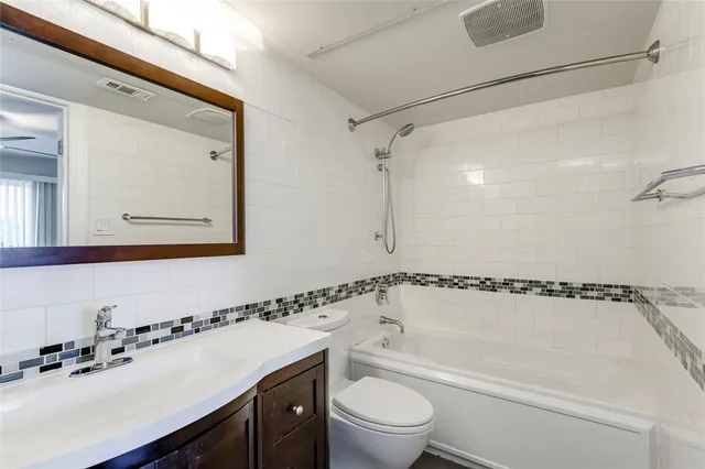 a bathroom with a bathtub shower sink vanity mirror and toilet