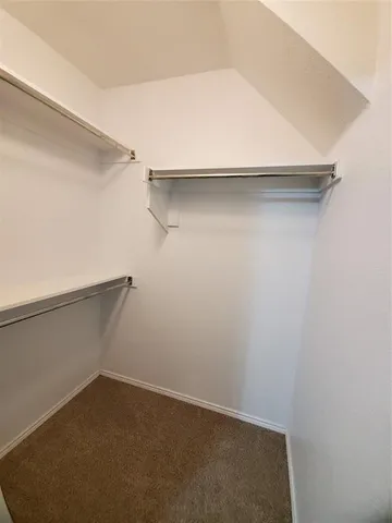 an empty room with a chandelier fan and windows