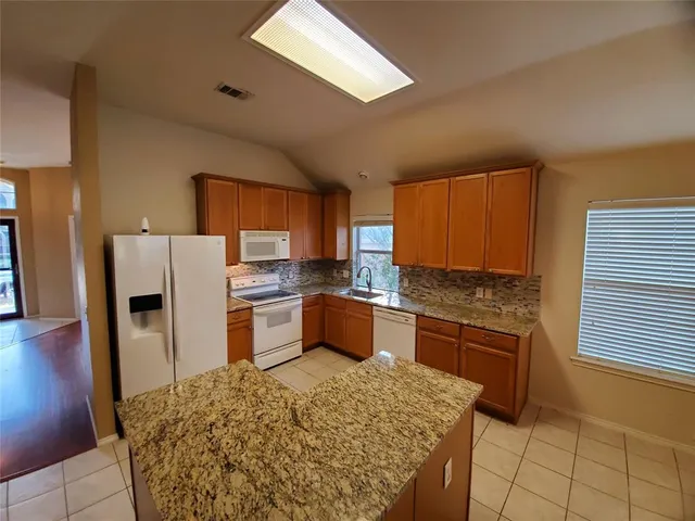 a kitchen with stainless steel appliances kitchen island granite countertop a stove refrigerator and dishwasher