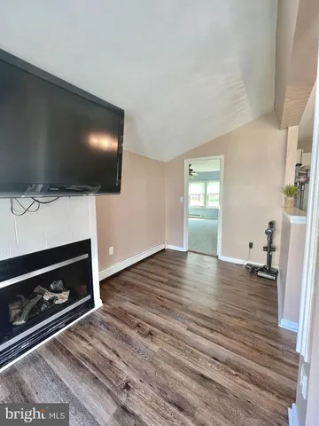a living room with fireplace furniture flat screen tv and wooden floor