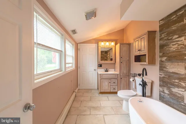 a spacious bathroom with a granite countertop sink a large mirror and a bathtub
