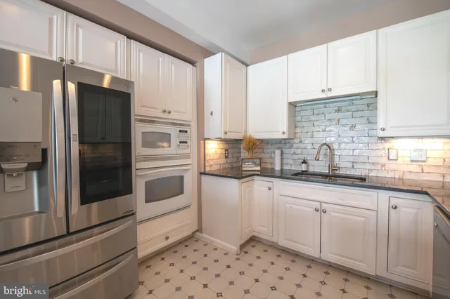 a kitchen with granite countertop white cabinets and stainless steel appliances