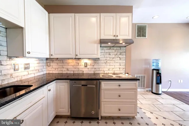 a kitchen with granite countertop white cabinets and sink