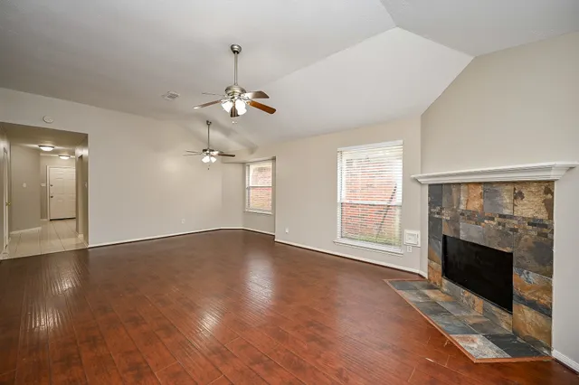 an empty room with wooden floor fireplace and windows