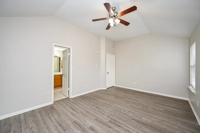 an empty room with wooden floor and a ceiling fan
