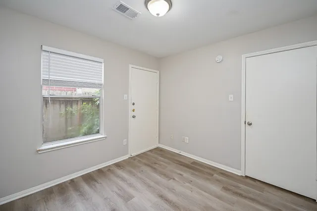 a view of an empty room with window and closet area