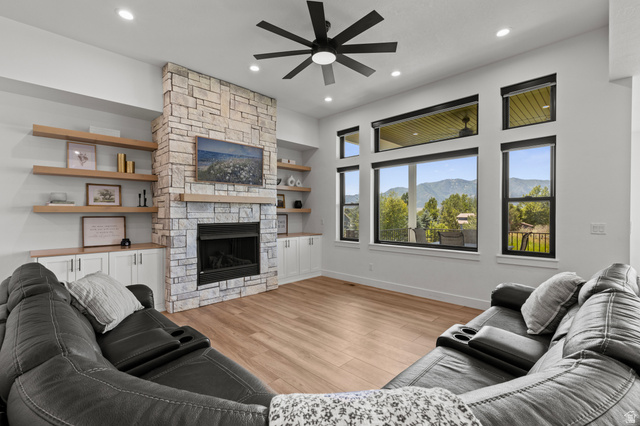 3111 South 1250 West Logan, UT 84321 - Photo 6 of 51 Spacious living area featuring a stone fireplace with a wood mantle, built-in shelving and cabinetry, recessed lighting, and wood-finish flooring