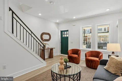 a living room with furniture couches and a dining table with wooden floor