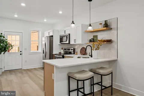 a kitchen with a sink and a stove with white cabinets
