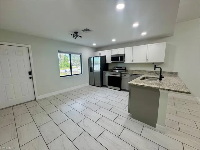 a kitchen with stainless steel appliances granite countertop a refrigerator a sink a stove a washer dryer and a cabinets