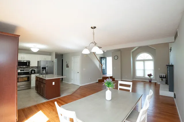 a kitchen with stainless steel appliances granite countertop a refrigerator a stove and a dining table with wooden floor