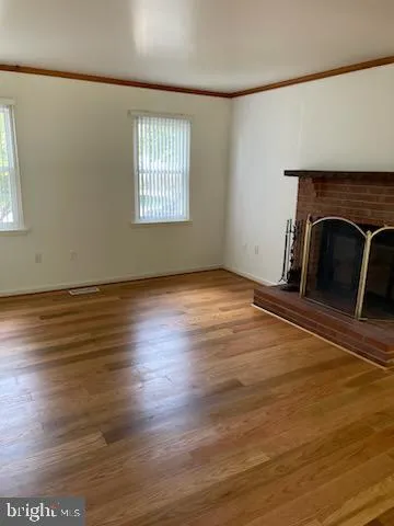 an empty room with wooden floor fireplace and windows