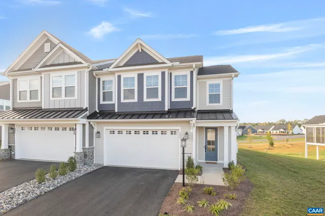 a front view of a house with a garden and lake view