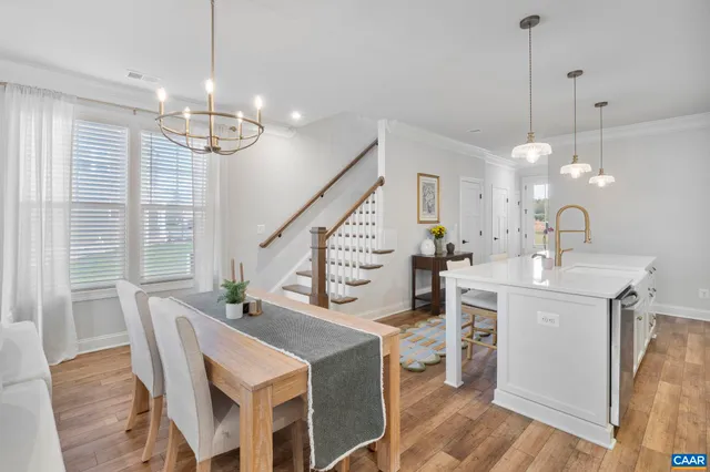 a view of a dining room and livingroom with furniture wooden floor a chandelier