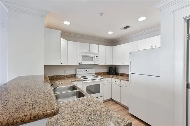 a kitchen with a sink a white cabinets and white appliances
