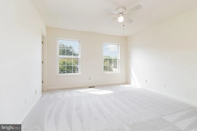 an empty room with windows and fan