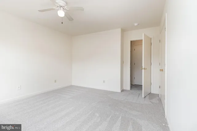 an empty room with a ceiling fan and carpet