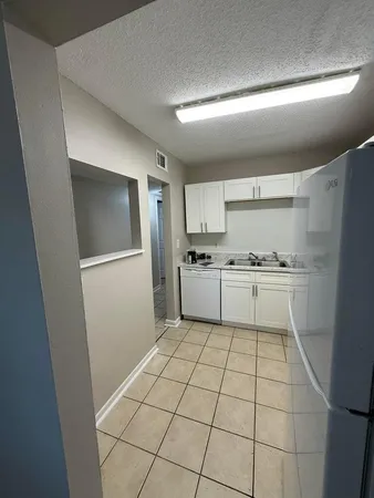a kitchen with a stove a refrigerator and white cabinets