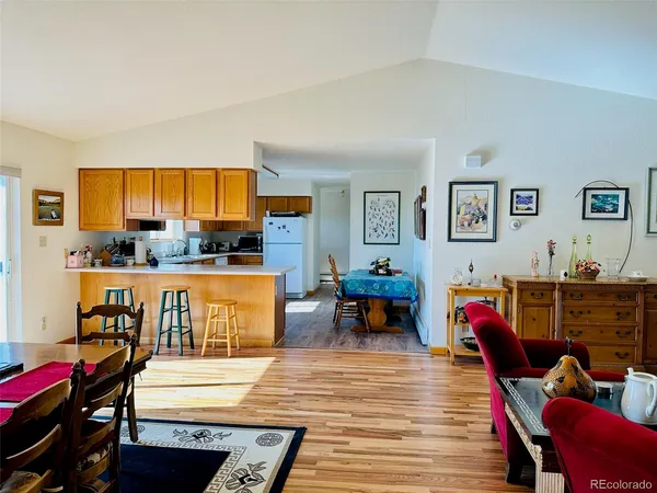 a living room with furniture kitchen view and a wooden floor