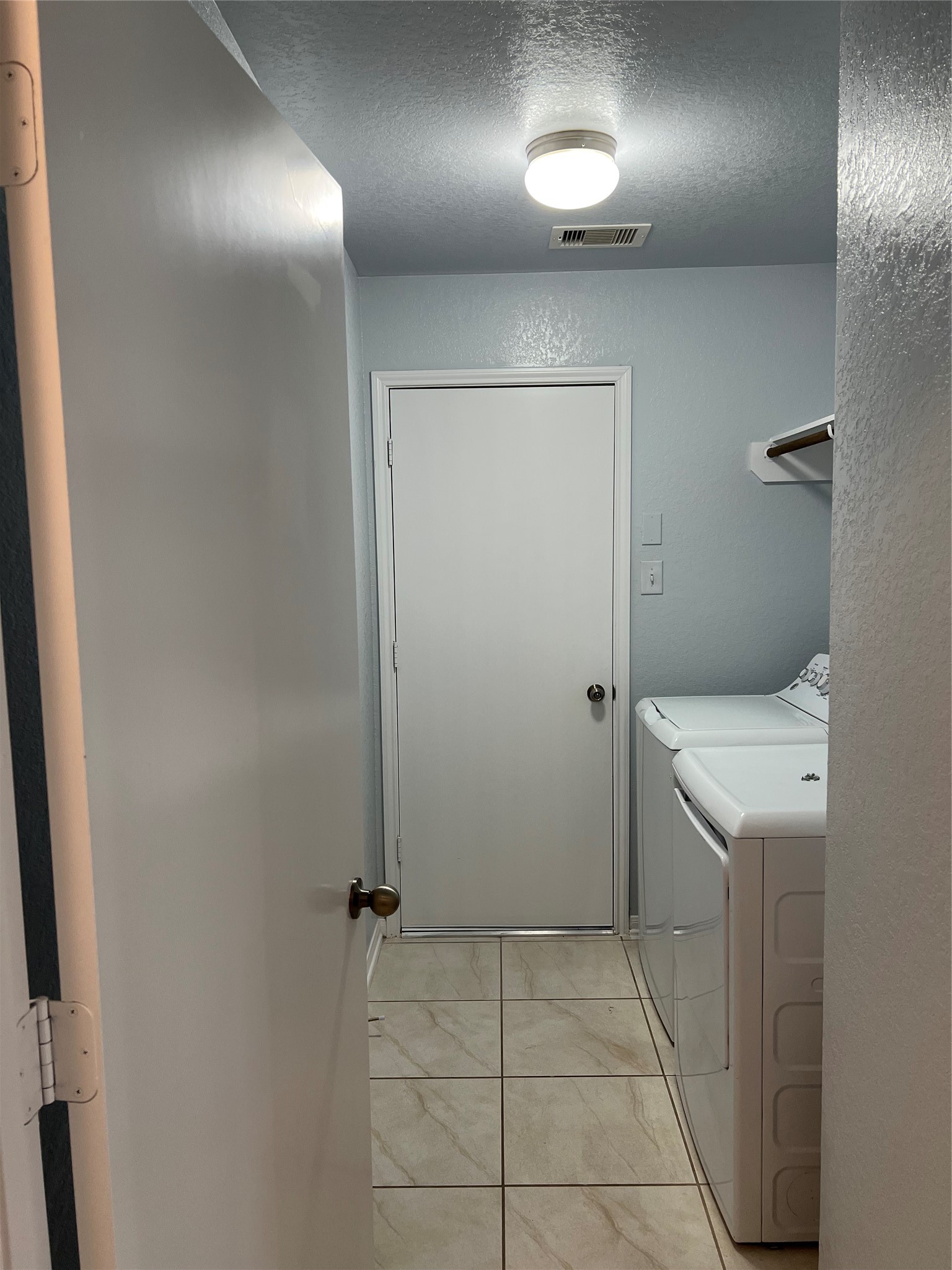 18303 Ranch View Trail Houston, TX 77073 - Photo 5 of 19 Bright and functional laundry room with washer & dryer featuring modern appliances and convenient shelving, set against elegant tiled flooring.