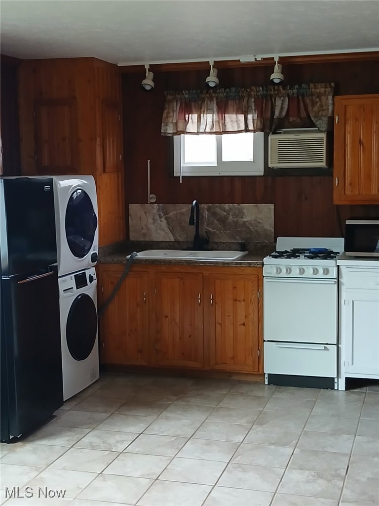 4370 Lake Road East Geneva, OH 44041 - Photo 14 of 14 Kitchen with light tile patterned floors, a sink, freestanding refrigerator, stacked washer / dryer, and white range with gas cooktop
