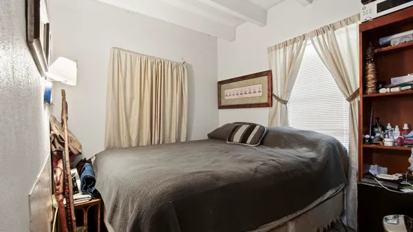 a bedroom with a bed and a flat tv screen on the dresser