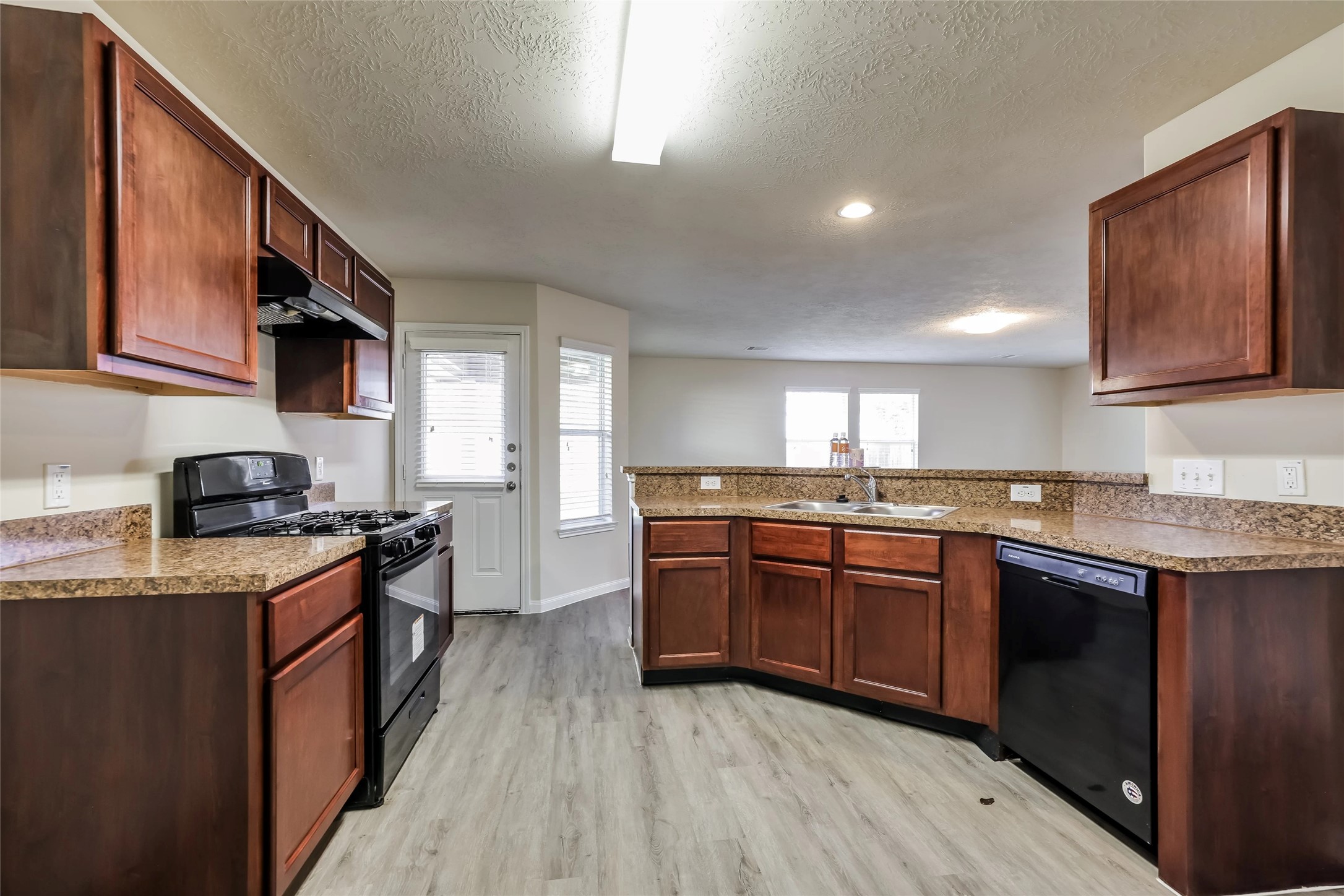 14438 Acuna Lane Houston, TX 77045 - Photo 3 of 15 a kitchen with stainless steel appliances granite countertop wooden cabinets a stove top oven a sink and dishwasher