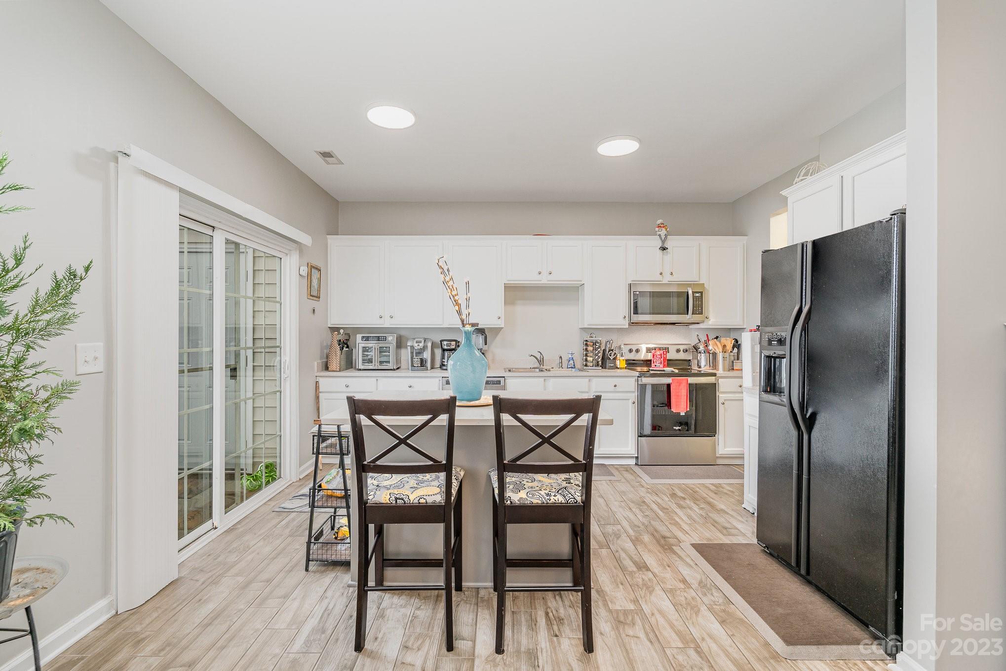 7572 Bluff Point Lane Denver, NC 28037 - Photo 12 of 33 a kitchen with stainless steel appliances a dining table chairs refrigerator and sink