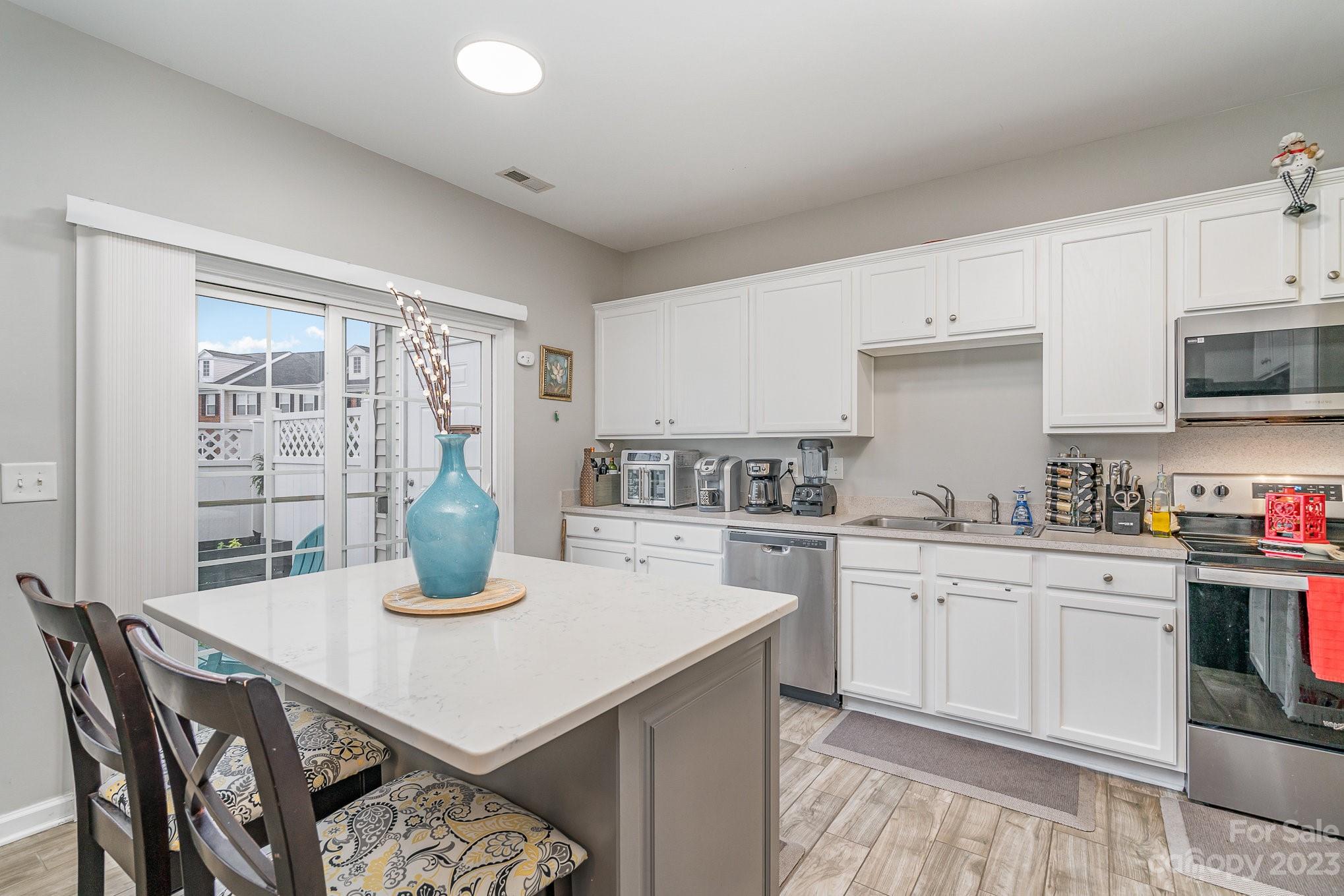 7572 Bluff Point Lane Denver, NC 28037 - Photo 13 of 33 a kitchen with a stove a sink dishwasher and white cabinets with wooden floor