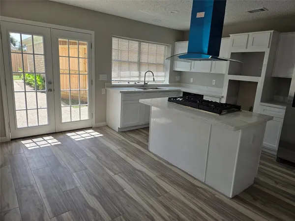a kitchen with granite countertop a sink cabinets and wooden floor