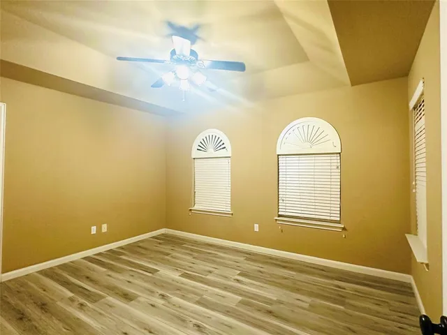 a view of an empty room with window and wooden floor
