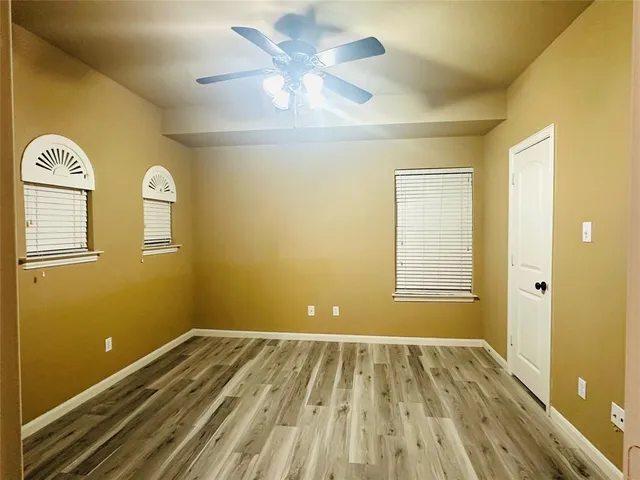 a view of a room with wooden floor and a ceiling fan