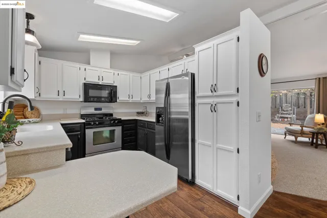a kitchen with a refrigerator a stove and a sink with wooden floor