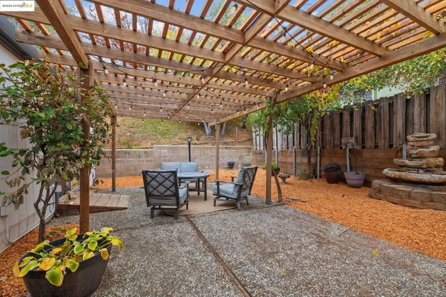 a view of a patio with table and chairs potted plants and large tree