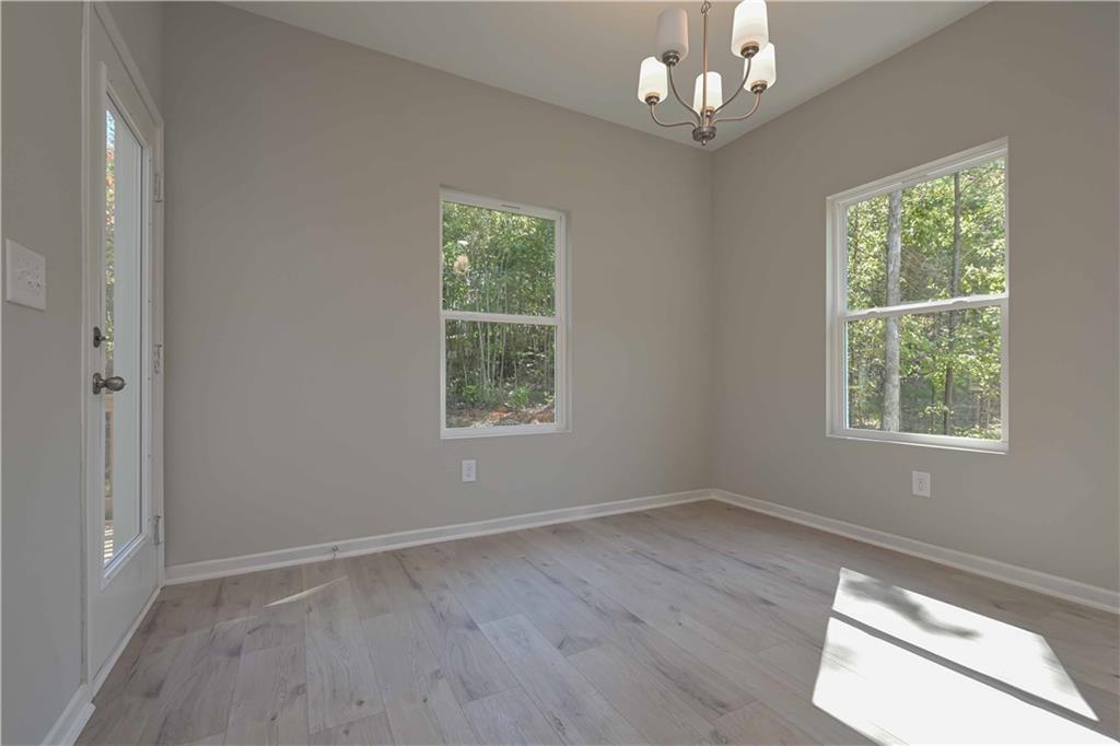 448 The Boulevard Newnan, GA 30263 - Photo 17 of 39 an empty room with wooden floor chandelier and windows