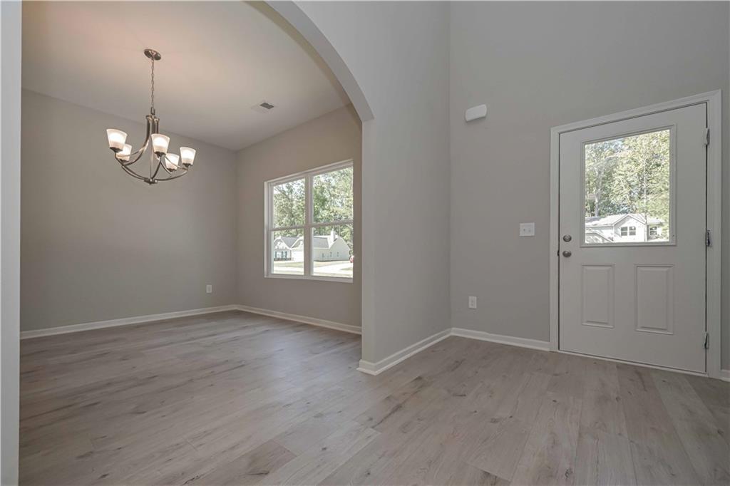 448 The Boulevard Newnan, GA 30263 - Photo 9 of 39 an empty room with wooden floor chandelier and windows