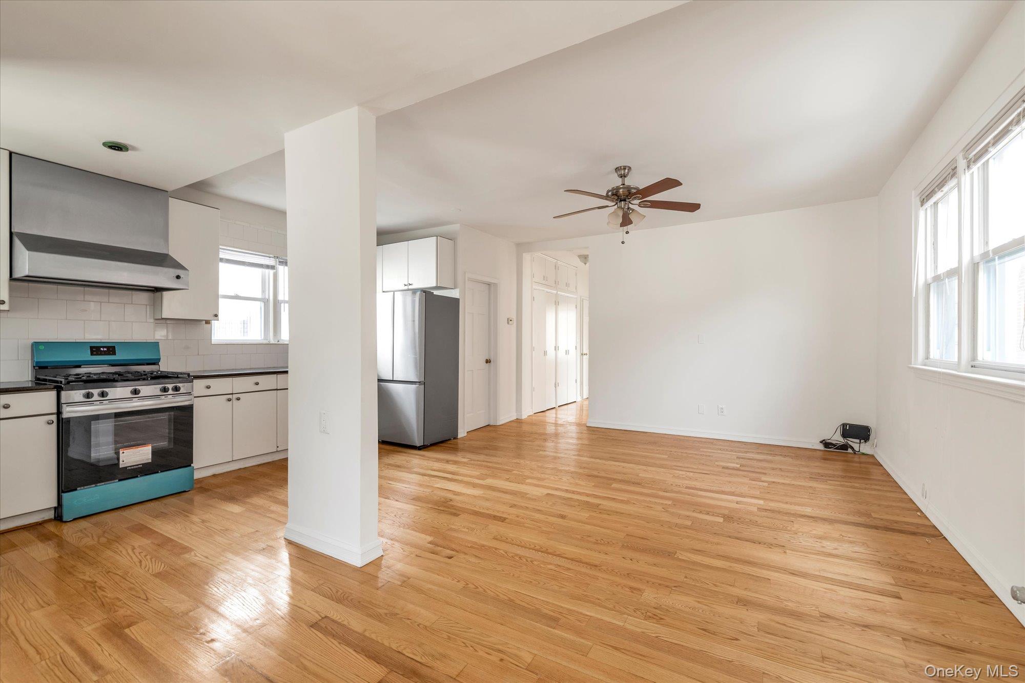 48-18 202nd Street Queens, NY 11364 - Photo 3 of 23 a view of a kitchen with a stove a ceiling fan and wooden floor